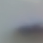 A blurry image with indistinct shapes and colors, mainly light gray and blue, with a darker area near the center. No clear objects or details are visible.