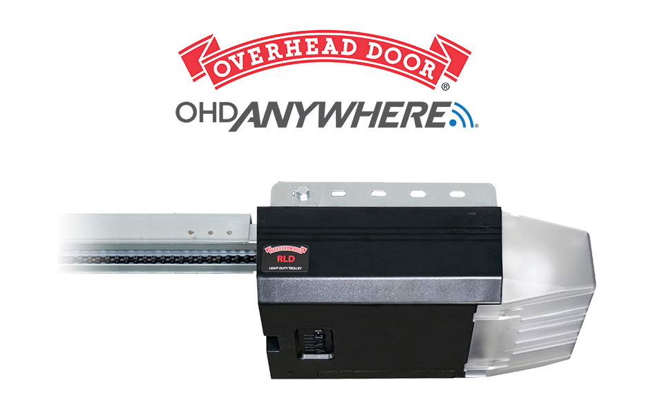 A garage door opener device with Trolley Operator and the Overhead Door and OHD Anywhere logos above it. The opener is black and silver, featuring a rail extending left and a small antenna icon on the logo.