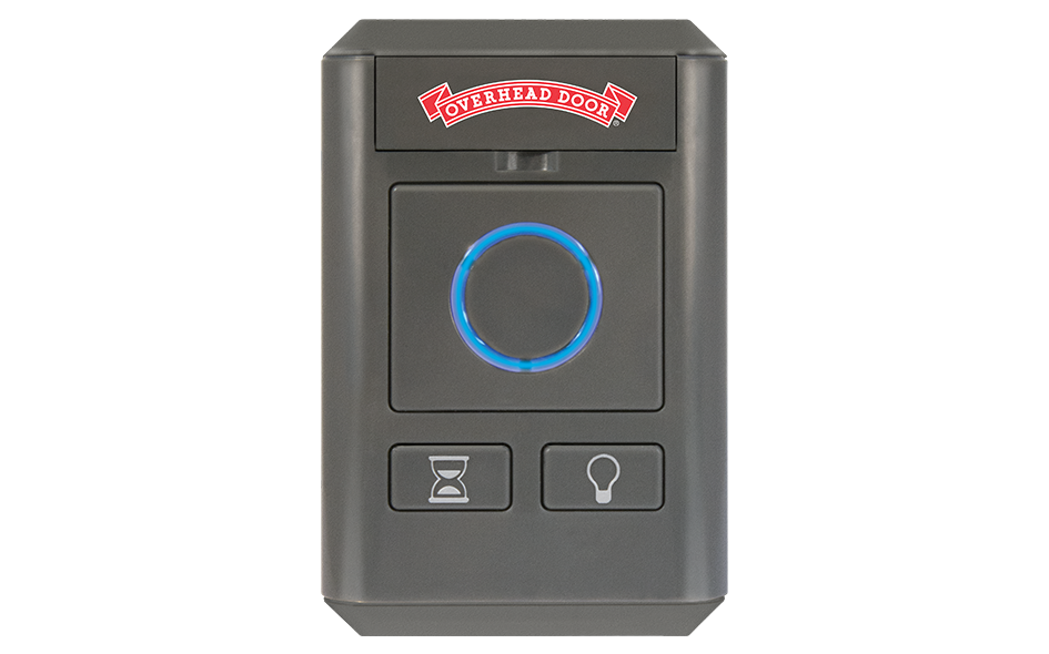 A black Wireless Wall Console for your Garage Door Opener, featuring a blue-lit circular button, hourglass and light bulb symbol buttons, plus a red Overhead Door logo at the top.